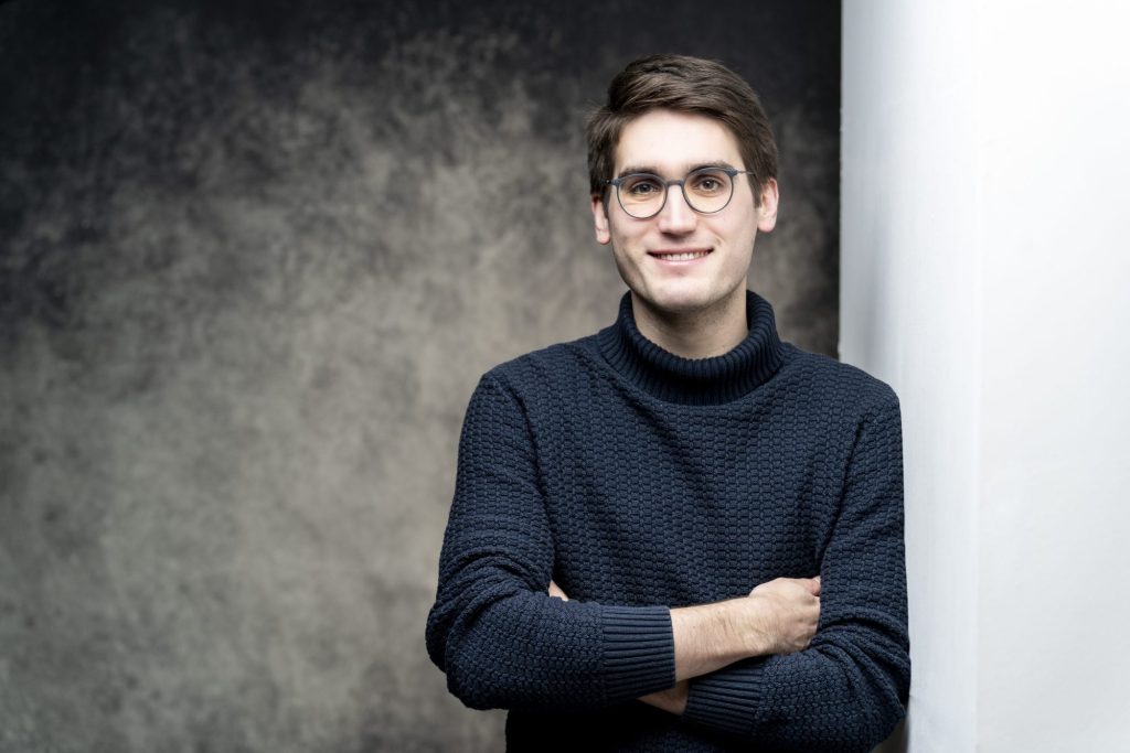 Businessportrait eines jungen Mannes mit Brille und Strickpullover vor dunklem Studiohintergrund – Fotostudio Karlsruhe-Durlach